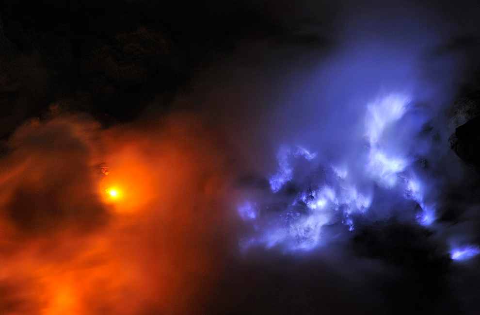 Шахтер в респираторе идет через густое облако аэрозоля и кислотного газа. Рядом видно синее пламя от горящего потока расплавленной серы.