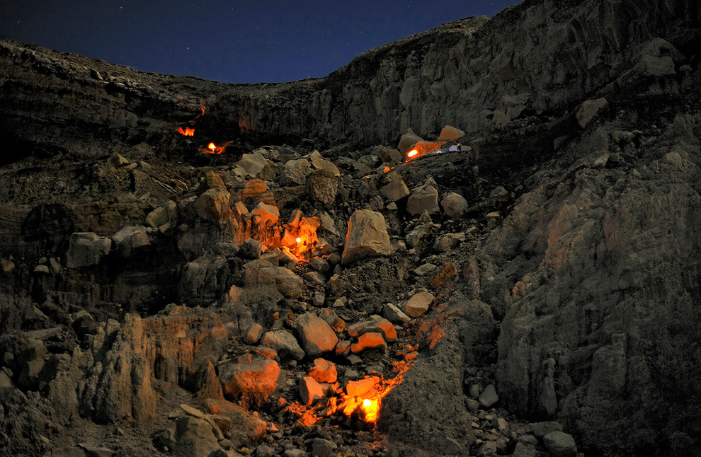 Шахтеры с факелами взбираются по стене кратера Кава Иджен. Они возвращаются по 200-метровому подъему к кайме кратера.