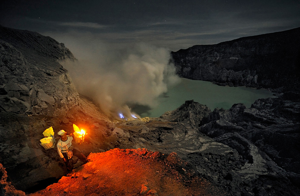 Вид сверху на добычу ископаемых в вулкане: горящая сера, кислотное озеро и залитые лунным светом стены кратера.